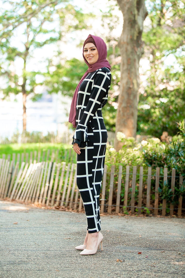 Woman in black and white checkered pantsuit and mauve chiffon hijab showcasing style