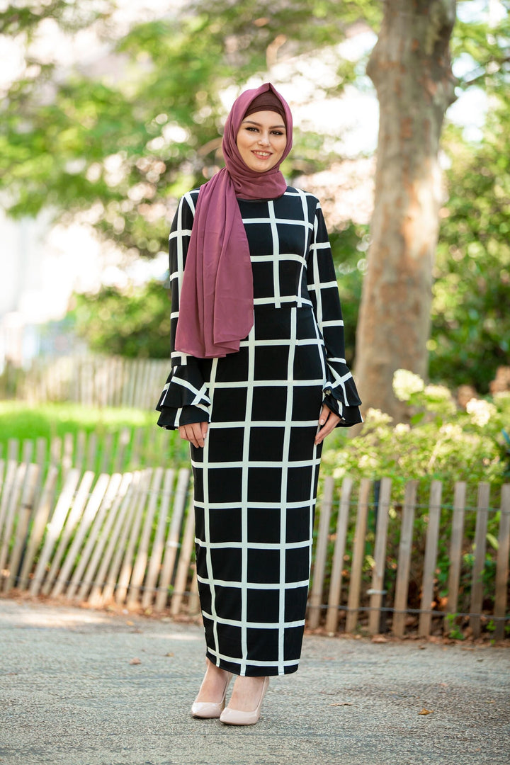 Woman in a bold black and white grid dress with a maroon hijab and criss-cross underscarf