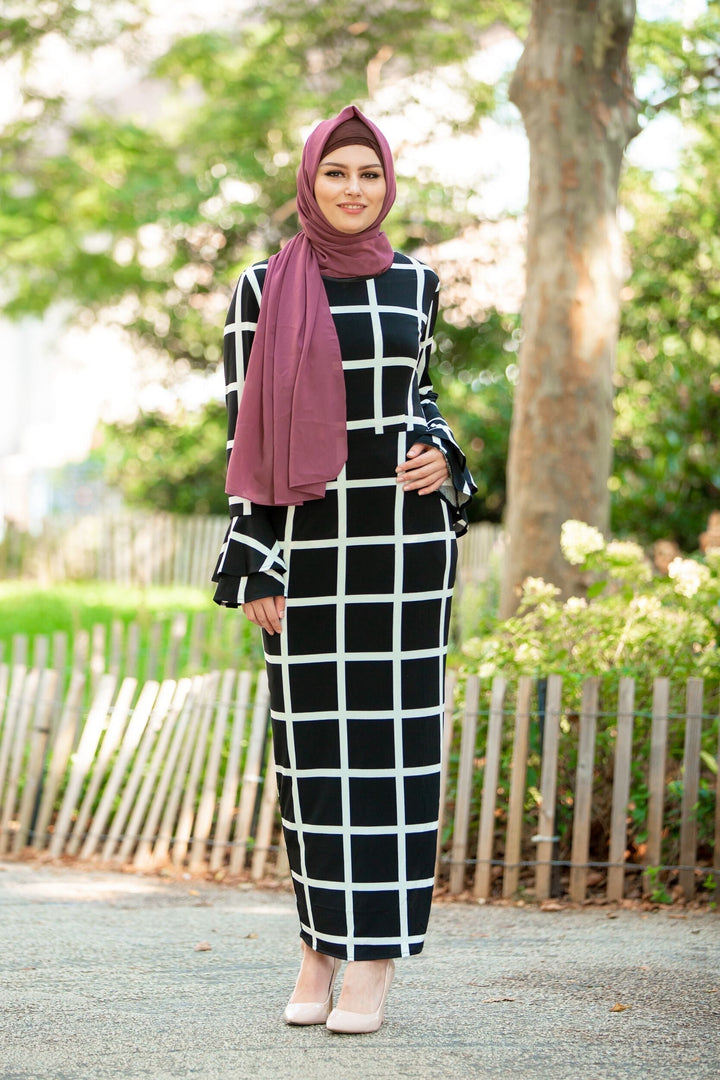 Woman in black and white grid dress with maroon hijab and brown criss-cross underscarf