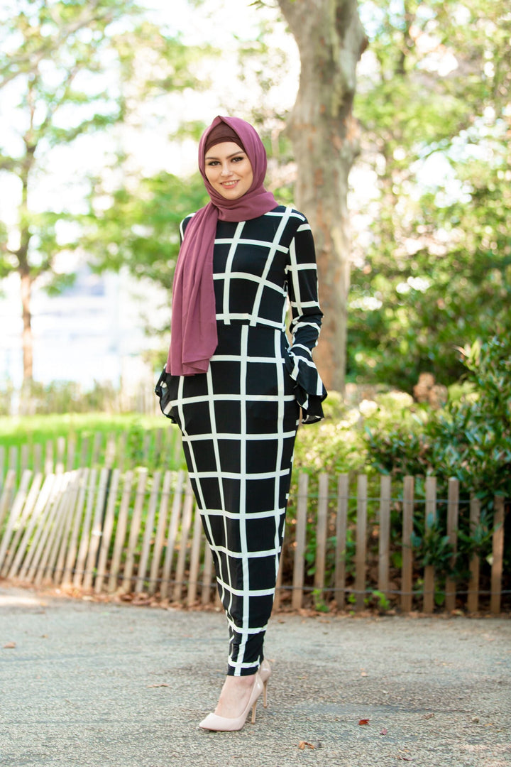 Woman in black and white grid dress with maroon hijab and brown criss-cross underscarf