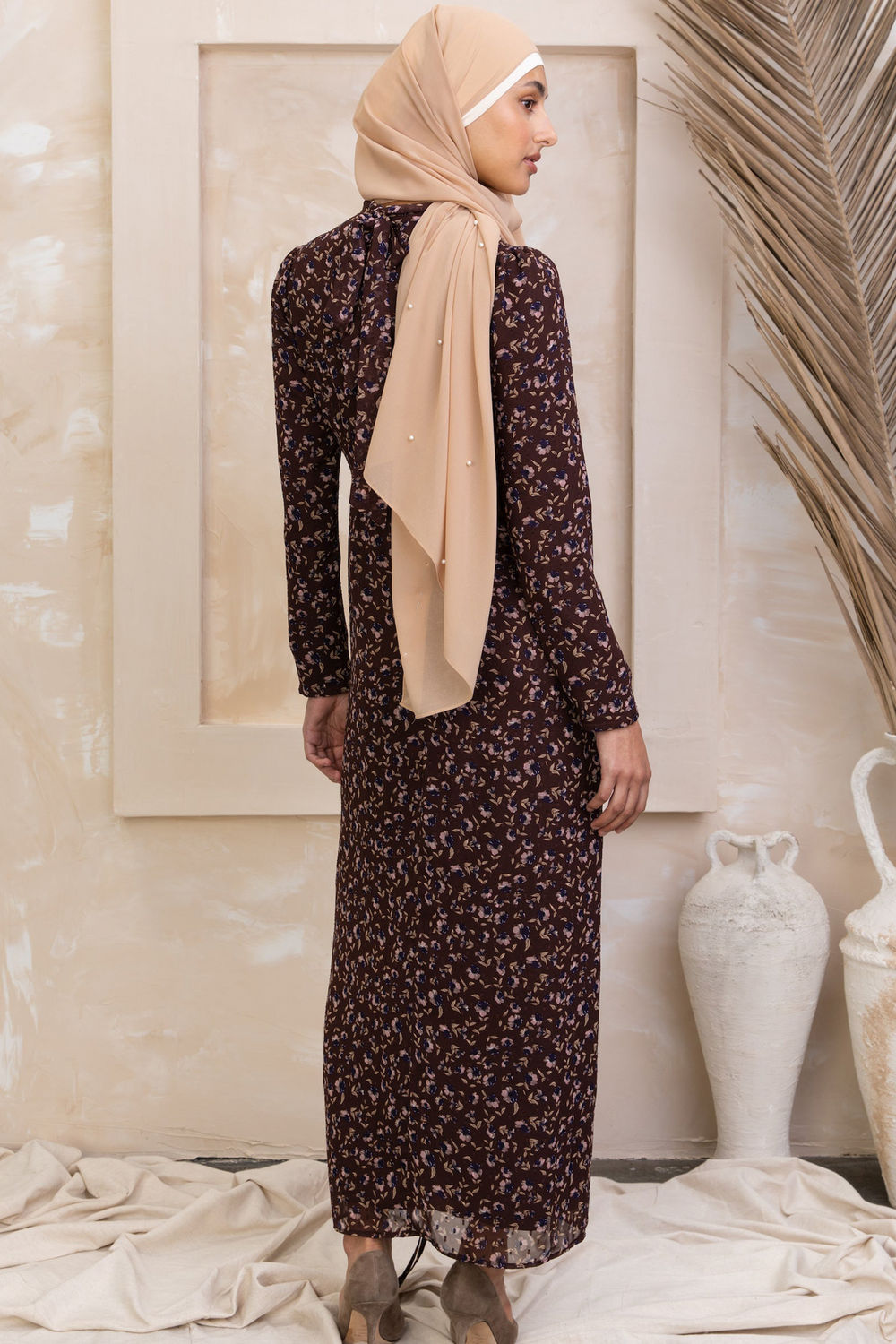 Woman in a brown floral ruched maxi dress with long sleeves and hijab