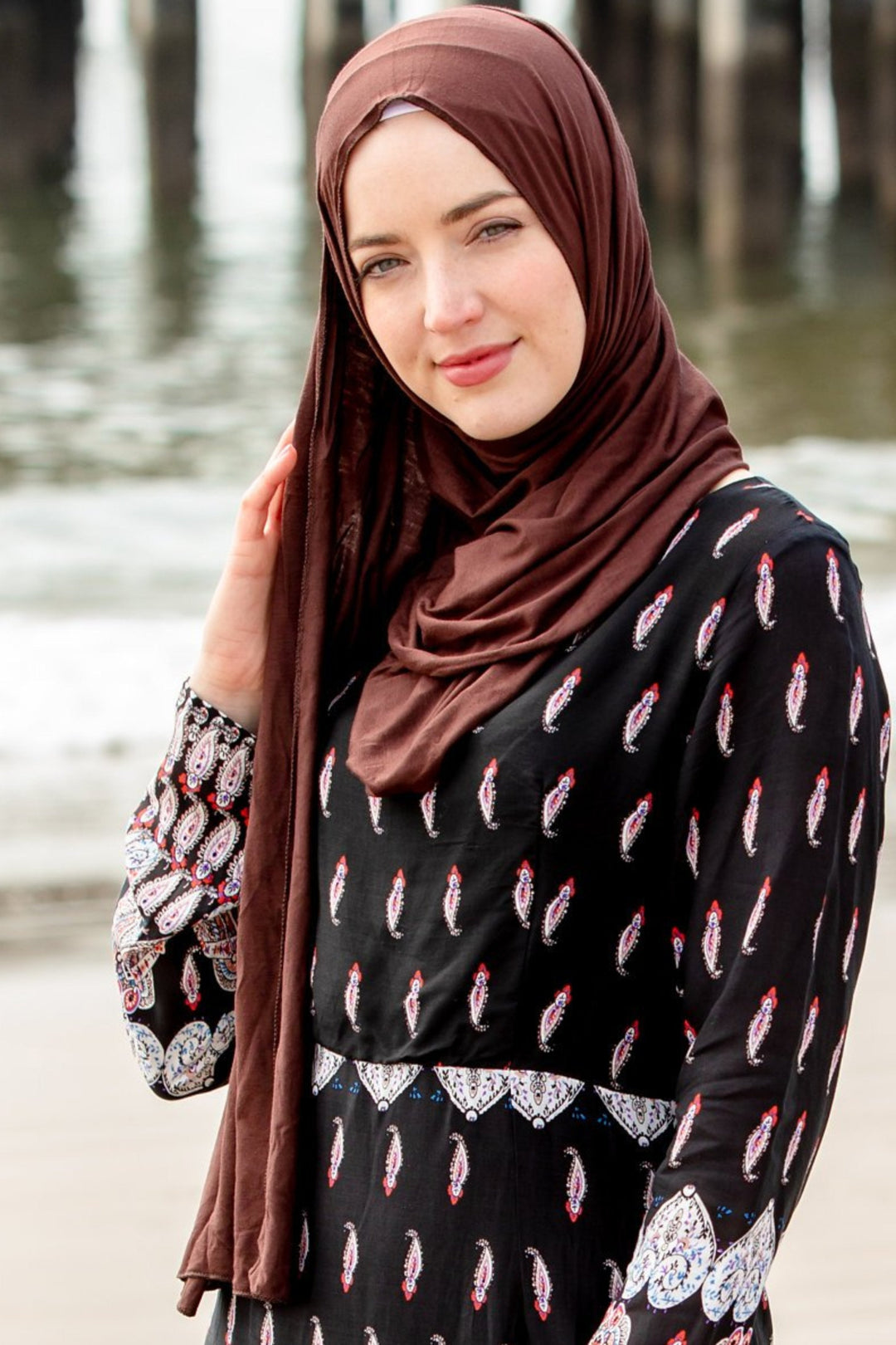 Woman wearing a brown hijab styled with a patterned dress showcasing the Brown Jersey Hijab