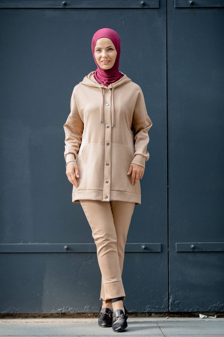 Woman in a beige hoodie sweatshirt and maroon hijab wearing a stylish pants set