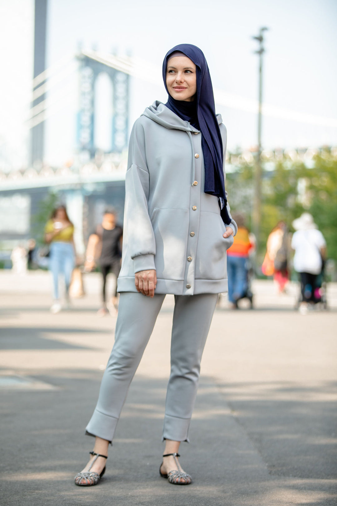 Woman in gray modest pants set featuring a navy hijab and button-down hoodie sweatshirt