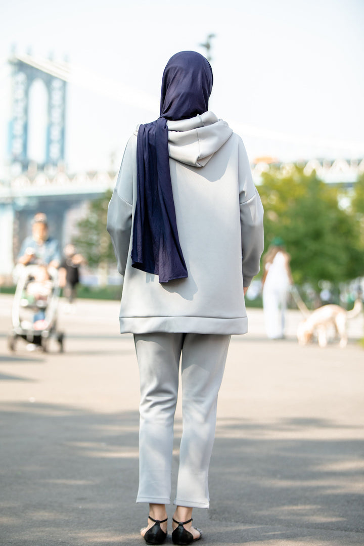 Woman in a gray hoodie sweatshirt and matching pants set with a navy hijab