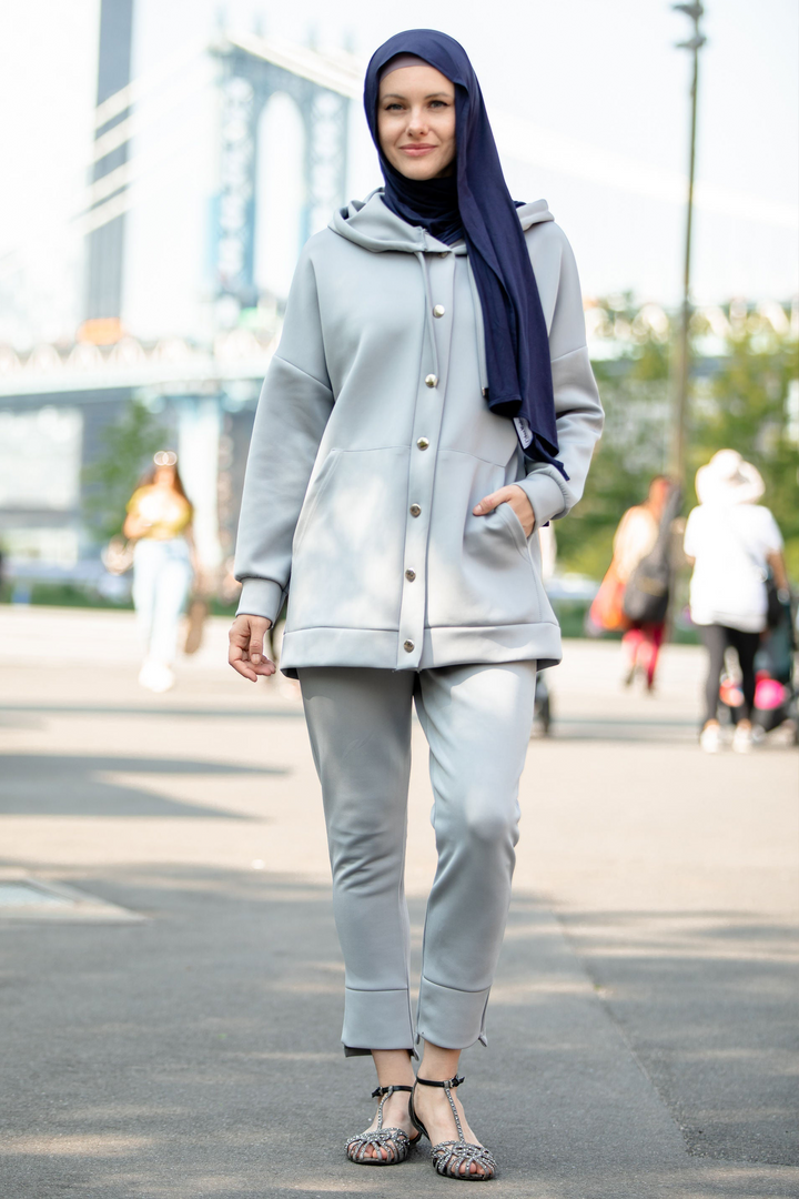 Woman in a gray pants set featuring a hoodie sweatshirt and navy hijab