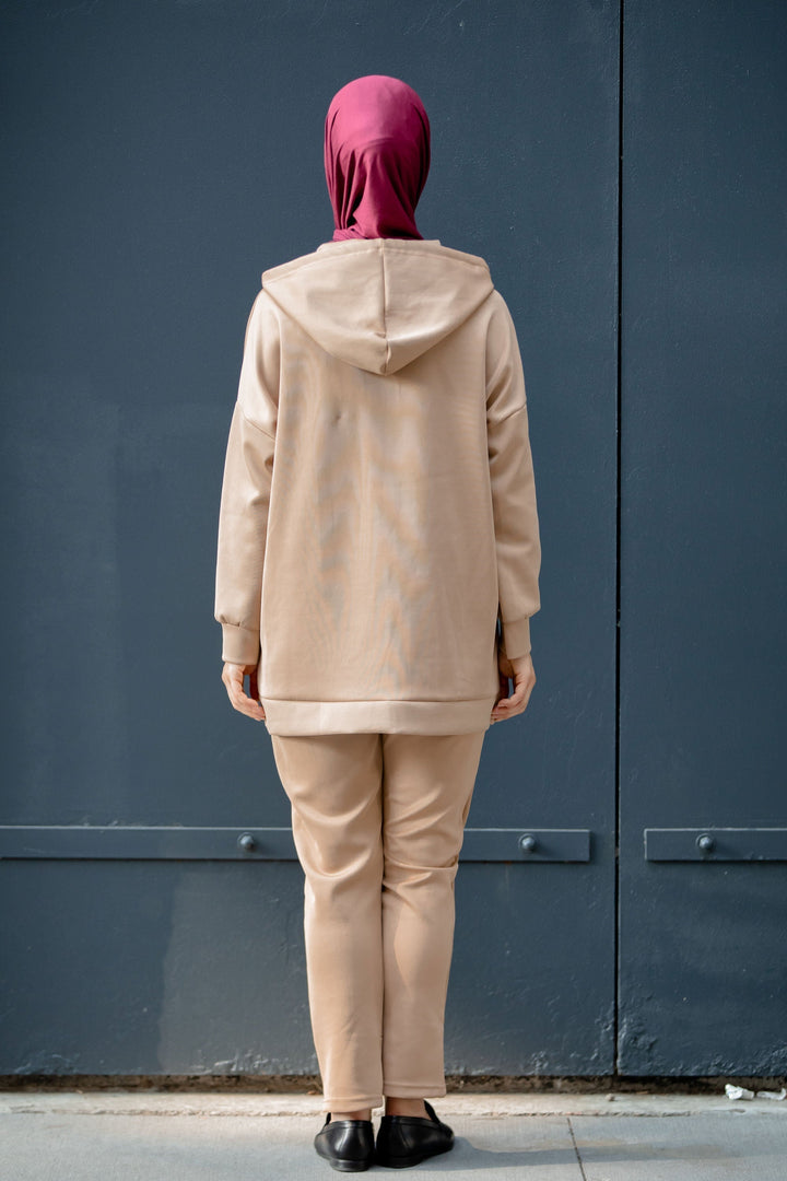 Woman in tan pants set with hooded sweatshirt and maroon hijab on clearance