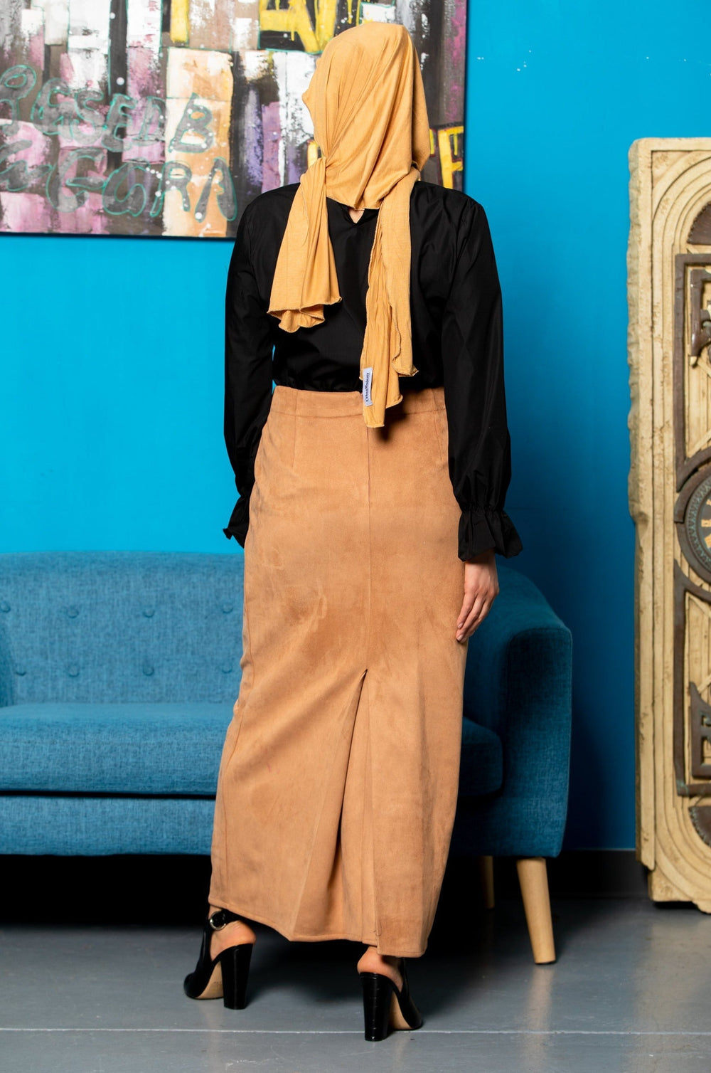 Woman in black blouse and tan skirt showcasing Camel Suede Pencil Maxi Skirt on clearance