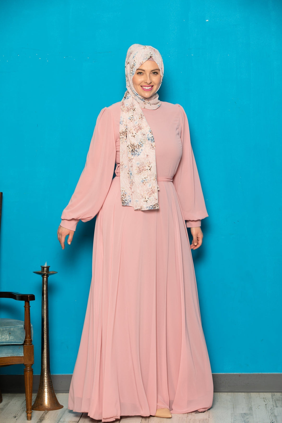 Woman in a pink chiffon long sleeve gown with a belt included, showcasing elegance