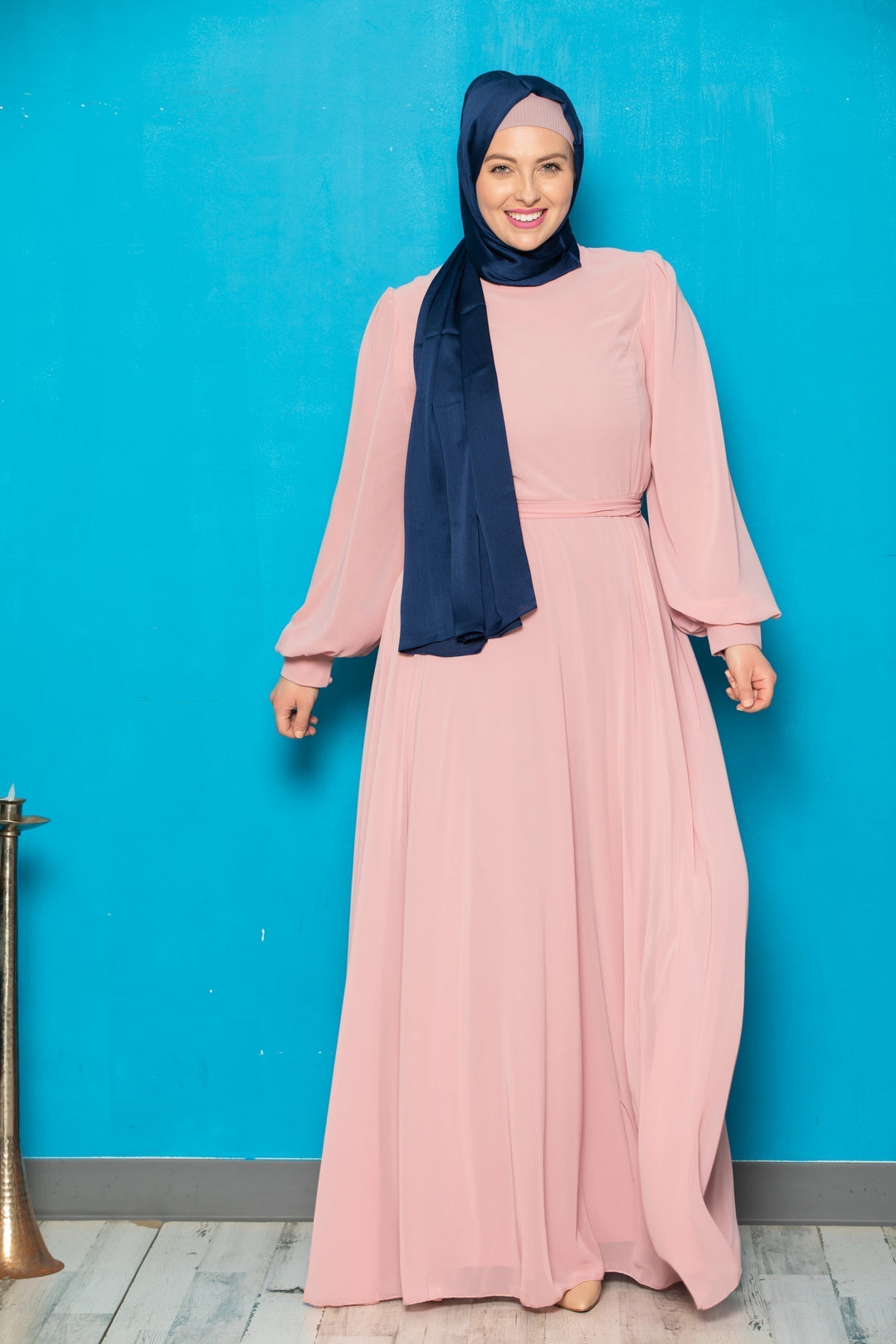 Woman in a long pink chiffon long sleeve gown with navy hijab and belt included