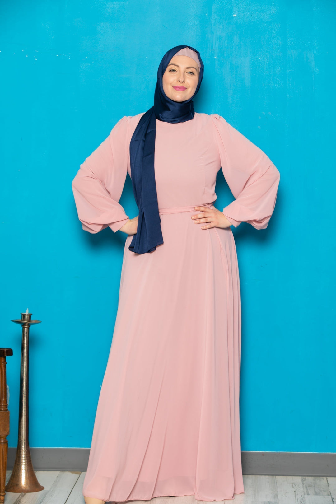 Woman in a long pink chiffon long sleeve gown with navy hijab and belt included