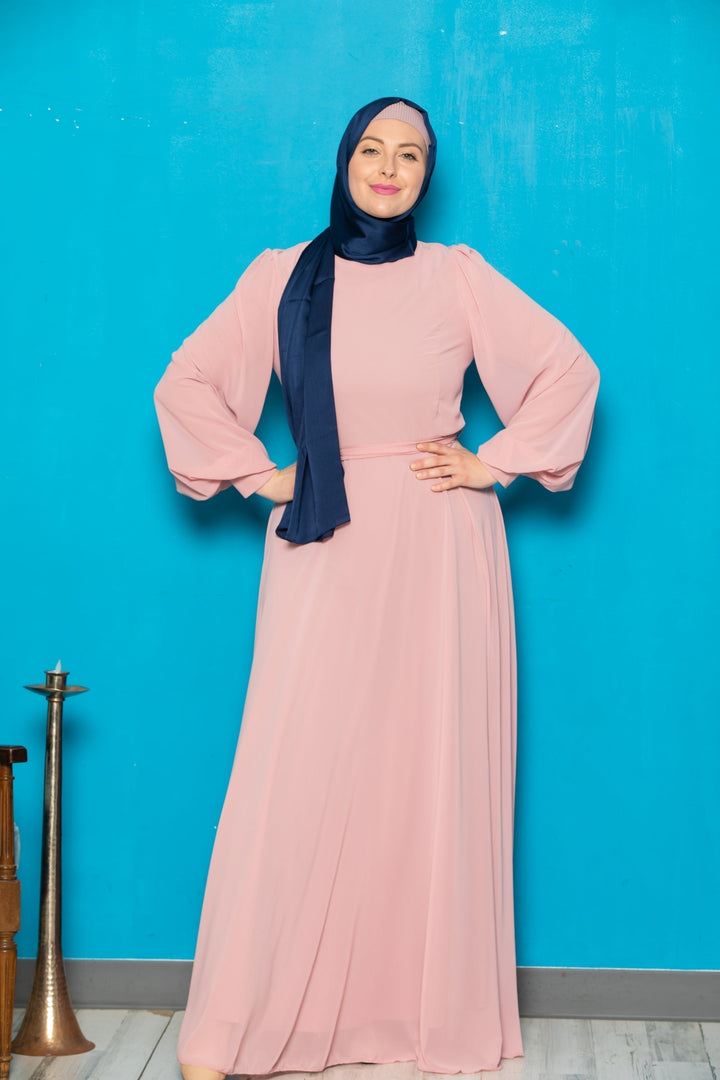 Woman in a long pink chiffon long sleeve gown with navy hijab and belt included