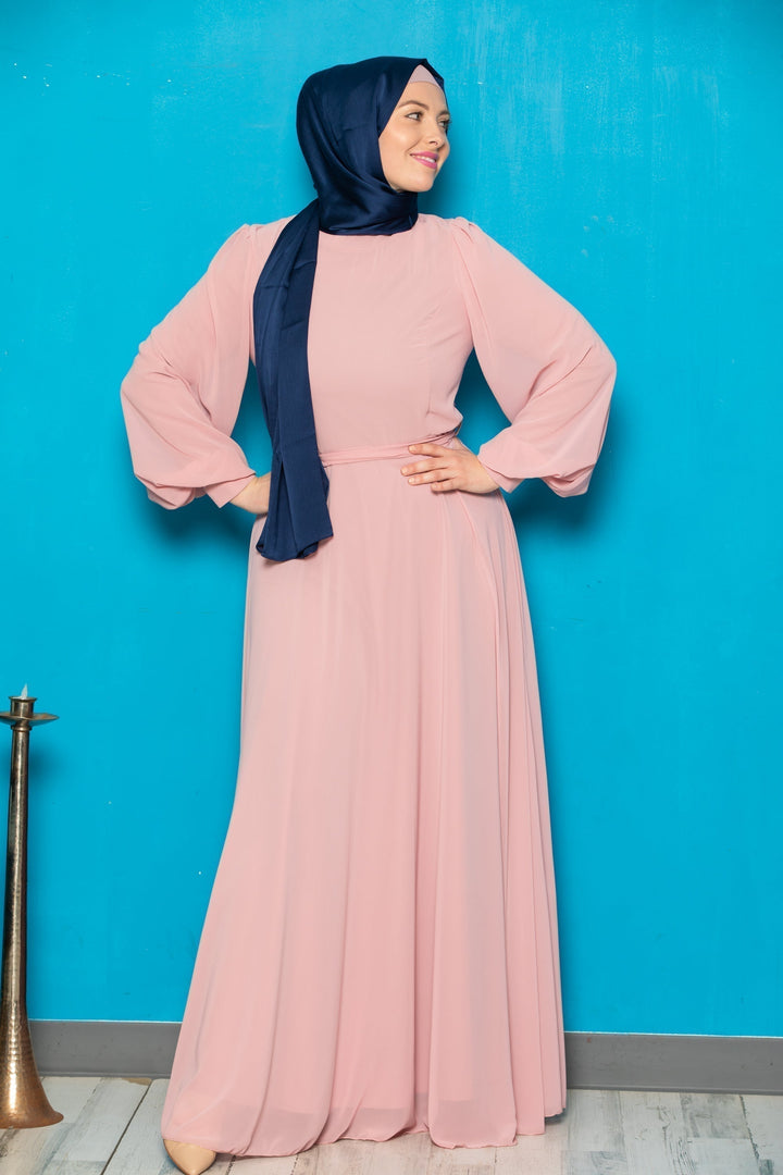 Woman in a long pink chiffon long sleeve gown with navy hijab and belt included