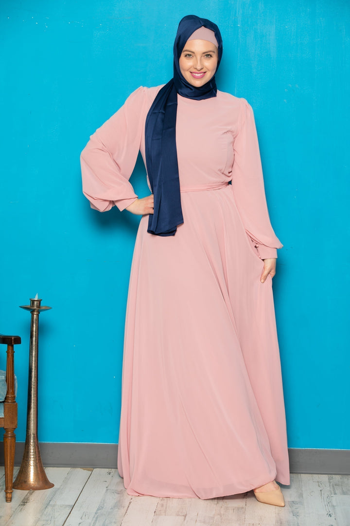 Woman in a chiffon long sleeve gown with a pink dress and dark blue hijab, belt included