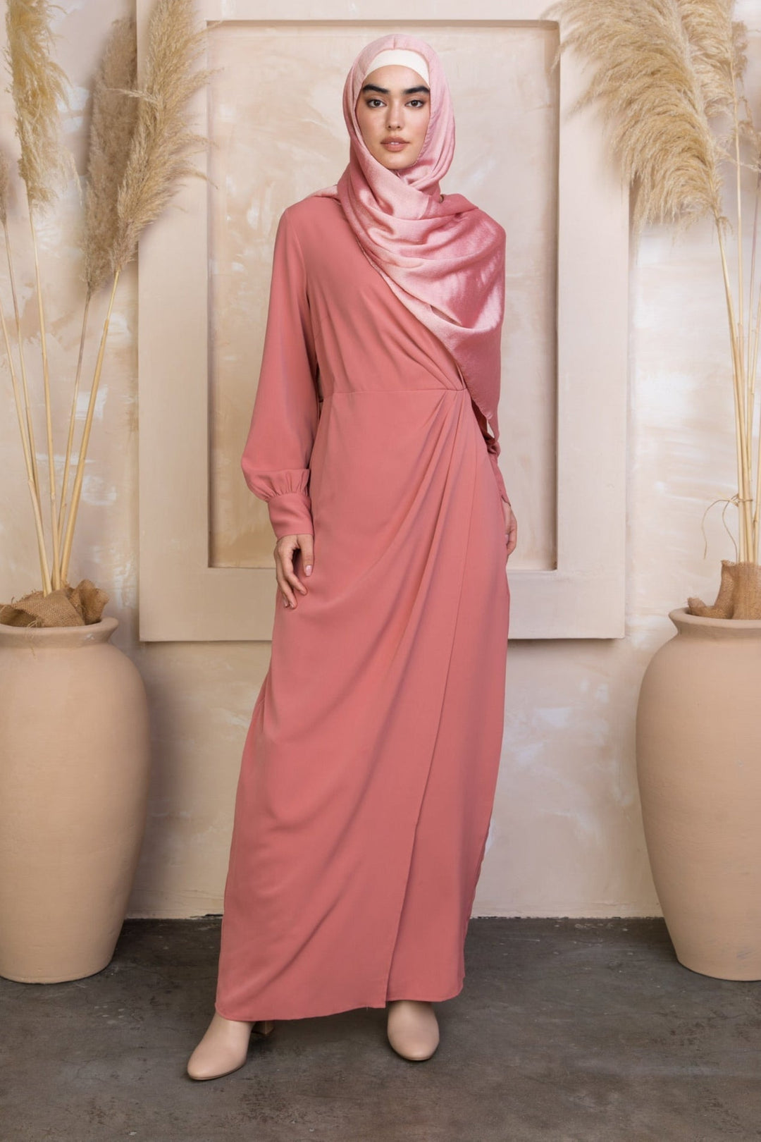 Woman wearing a coral wrap maxi dress with matching hijab and long sleeves