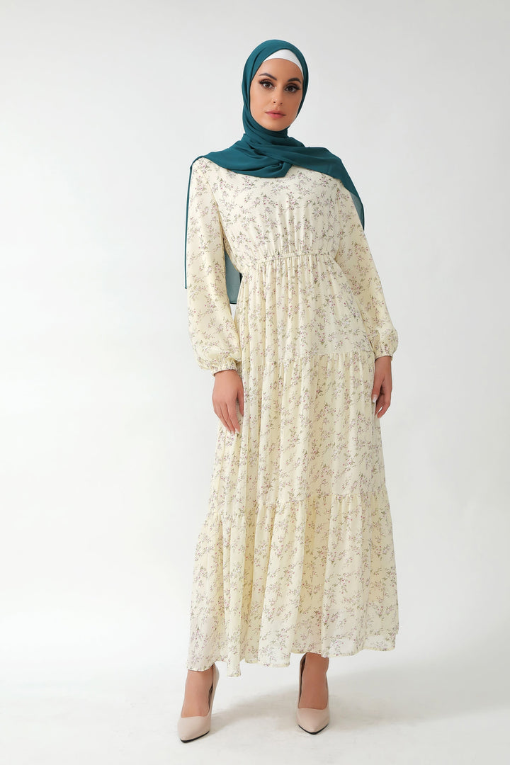 Woman in a floral tiered maxi dress with teal hijab and floral patterns