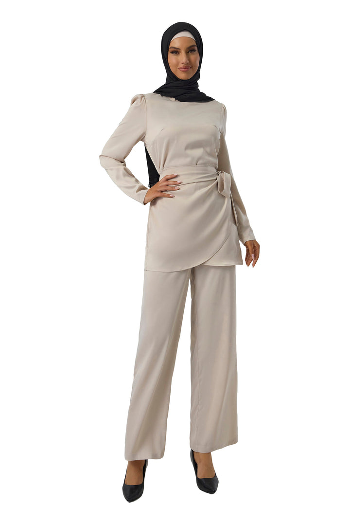 Woman in modest beige pant set with black hijab, featuring a cream wrap tunic