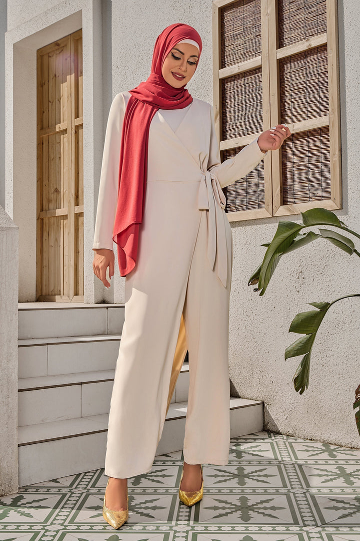 Woman in a beige knot jumpsuit with a red hijab showcasing effortless style