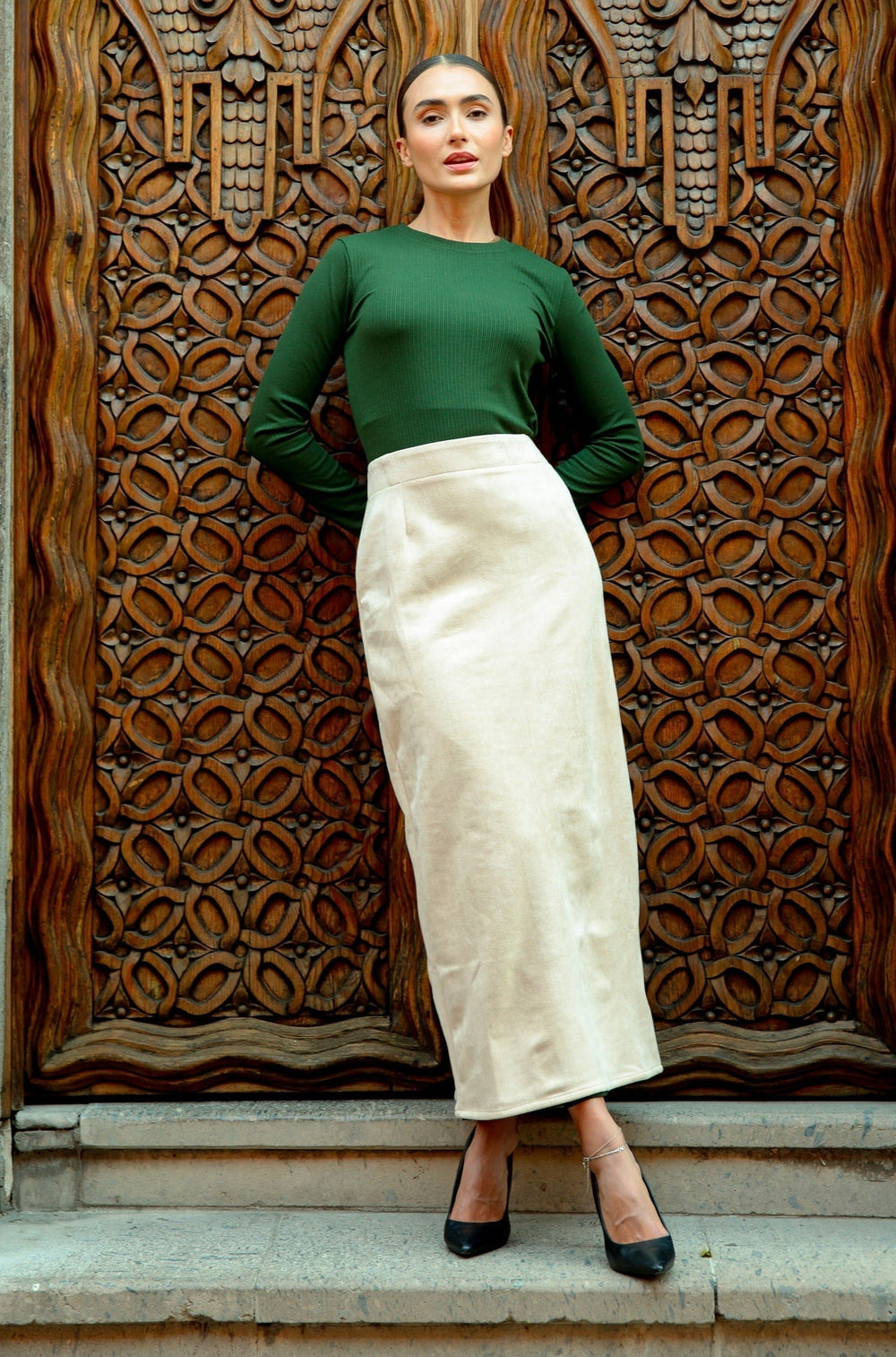 Woman in green top and cream skirt showcasing Cream Suede Pencil Maxi Skirt on clearance