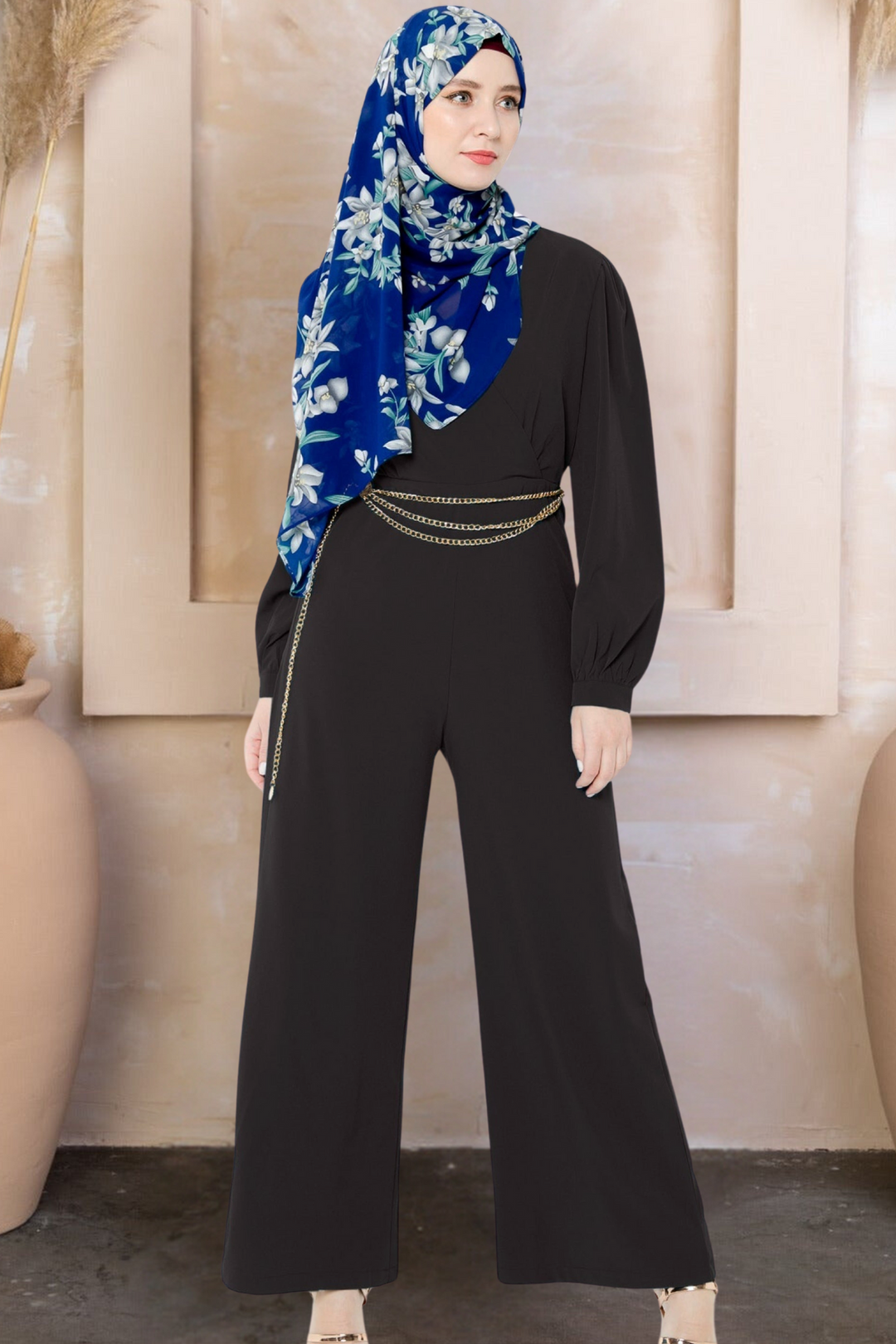 Woman in black long sleeve jumpsuit with criss-cross neckline and floral hijab