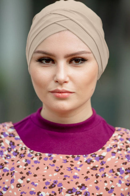 Woman in a beige tube hijab underscarf, featuring criss-cross design