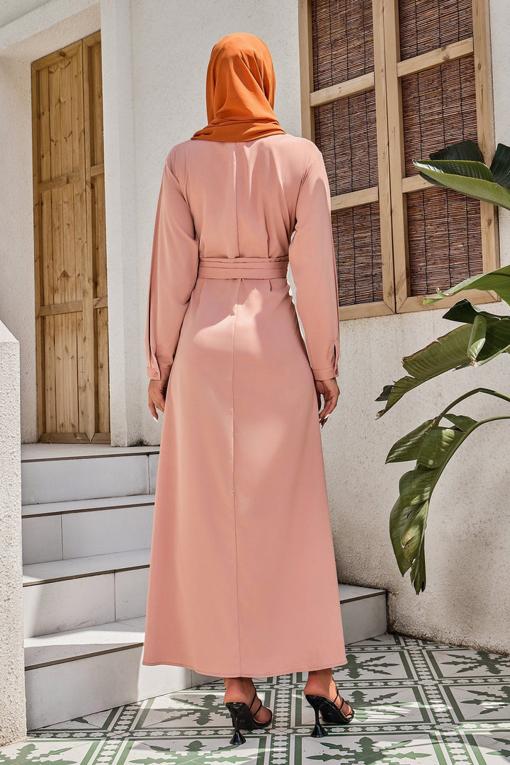 Woman wearing a dusty pink criss cross maxi dress with an orange hijab and belted style