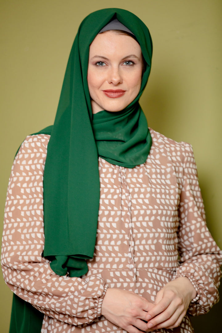 Woman wearing an Evergreen Chiffon Hijab in a stylish green scarf