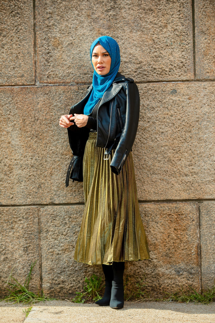 Woman in blue hijab wearing gold metallic pleated chiffon maxi skirt and black jacket