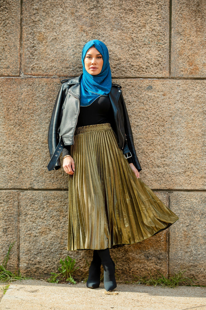 Woman in hijab wearing a leather jacket and gold metallic pleated chiffon maxi skirt