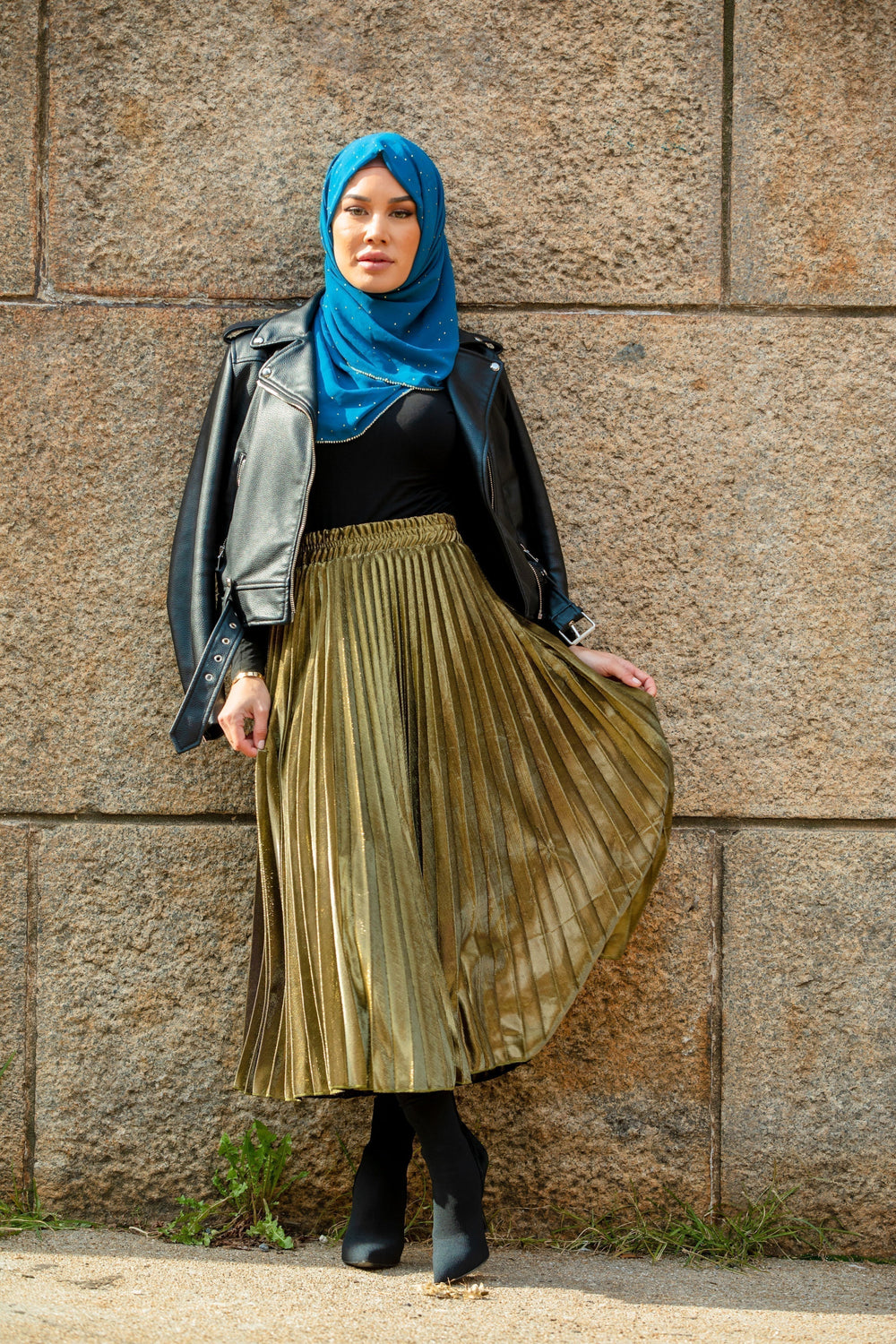 Stylish woman in hijab wearing gold metallic pleated chiffon maxi skirt and leather jacket