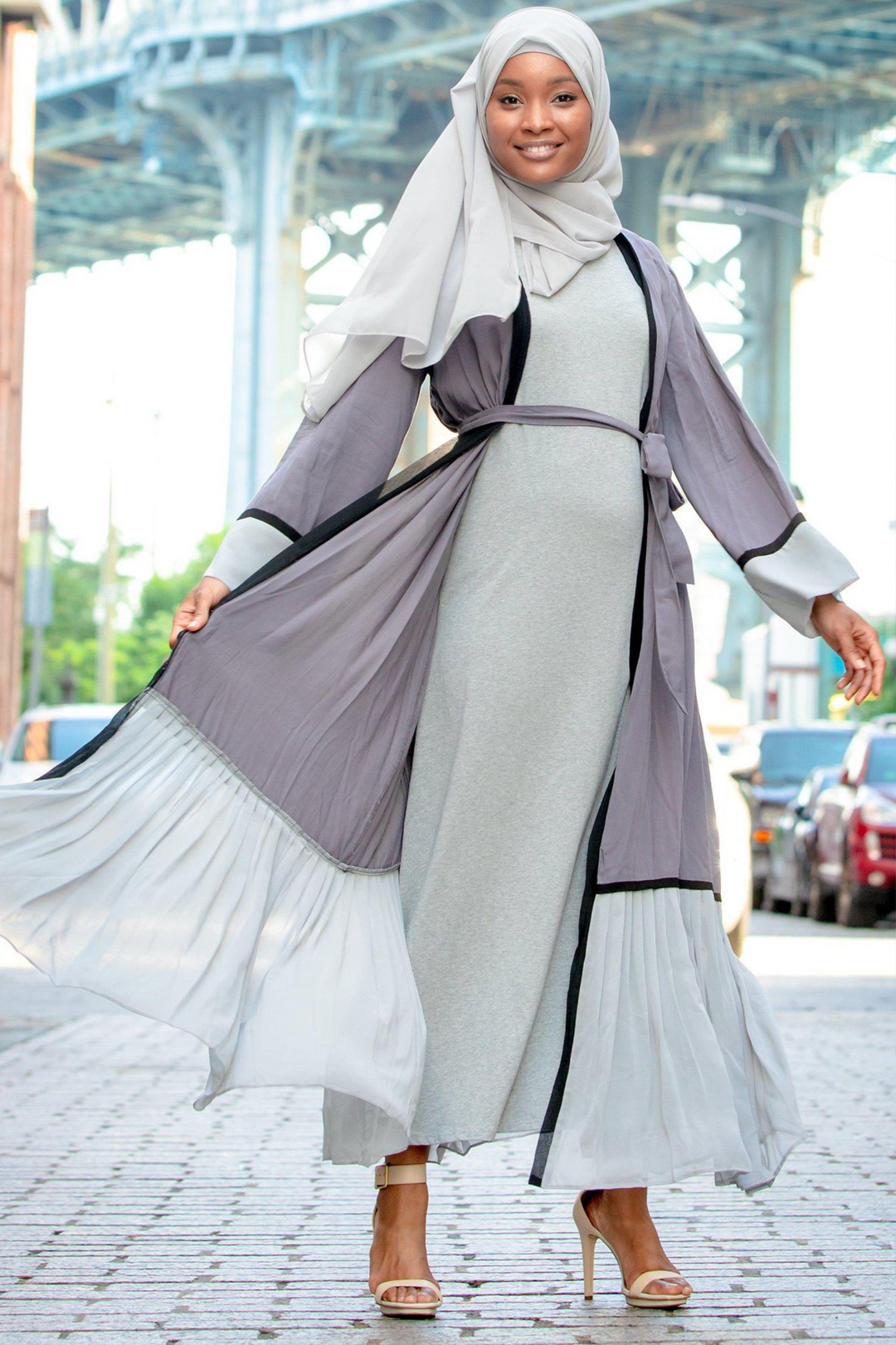 Smiling woman in gray ruffle open front Abaya showcasing modest fashion style