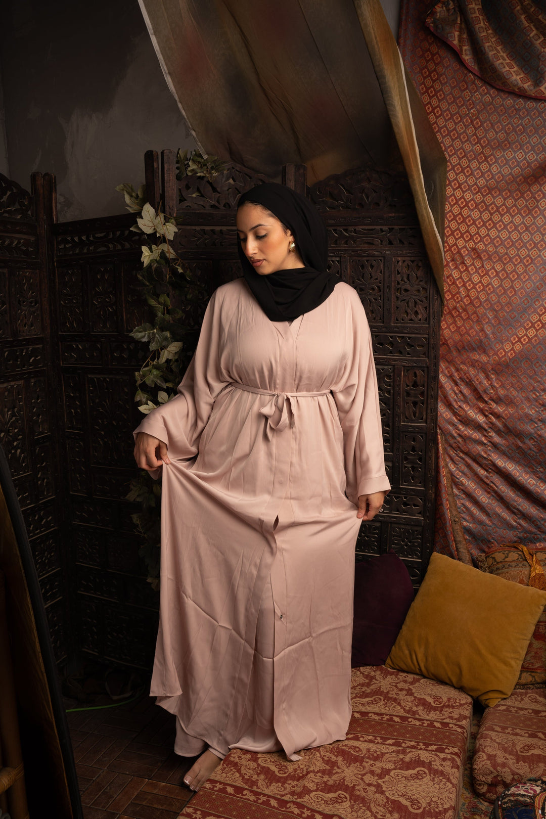 Woman wearing a long light pink dress and black hijab with a Khaki Sleeveless Dress Abaya Set