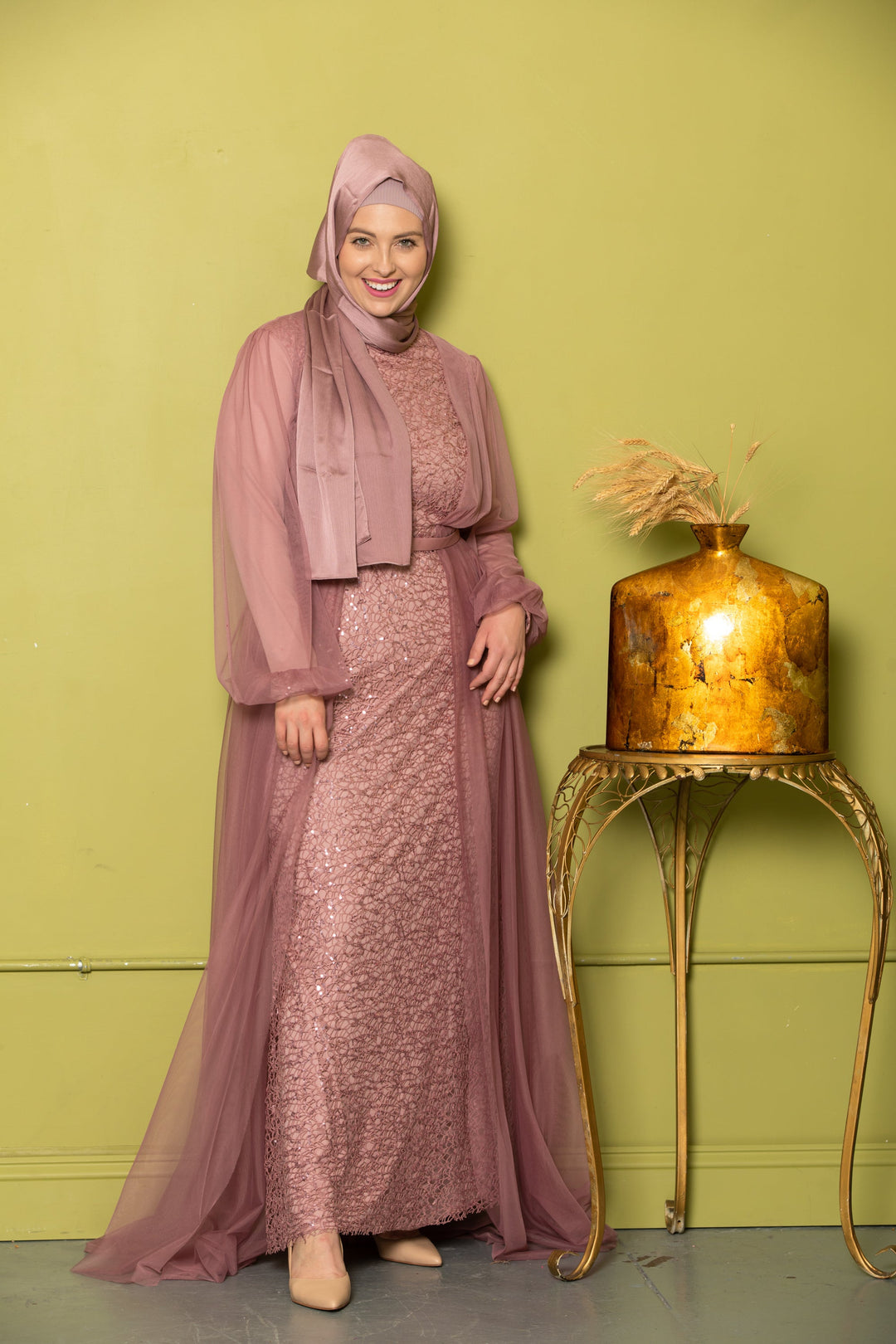 Woman in a mauve sequined dress and hijab wearing a chiffon overlay gown