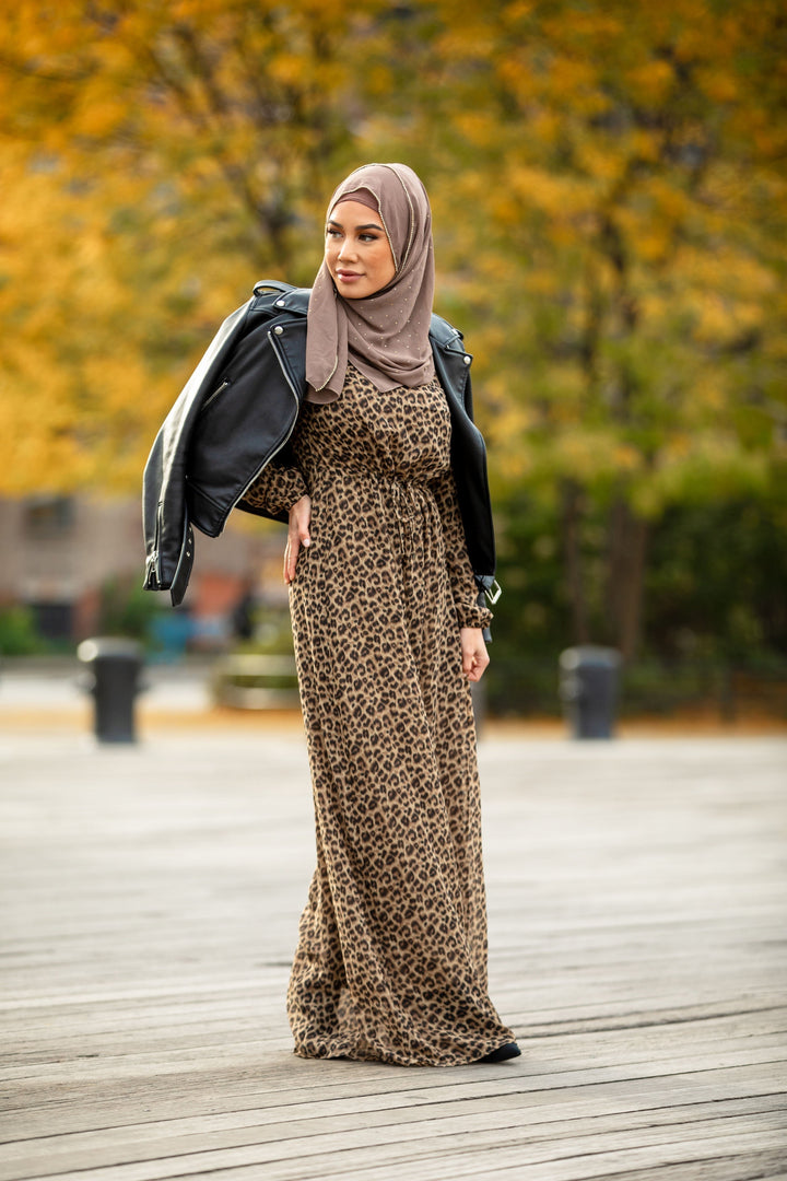 Woman in leopard print maxi dress with elastic cuffs and hijab, paired with a leather jacket