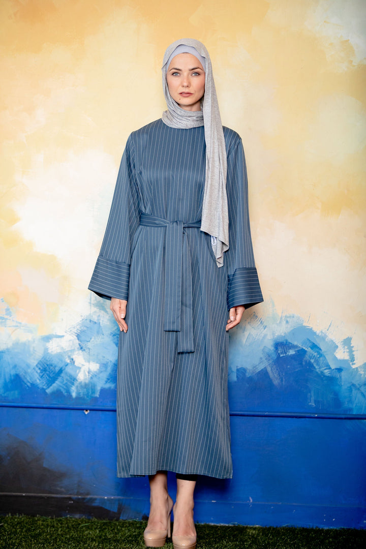 Woman in a striped blue dress and hijab wearing a blue pinstripe kimono sleeve abaya