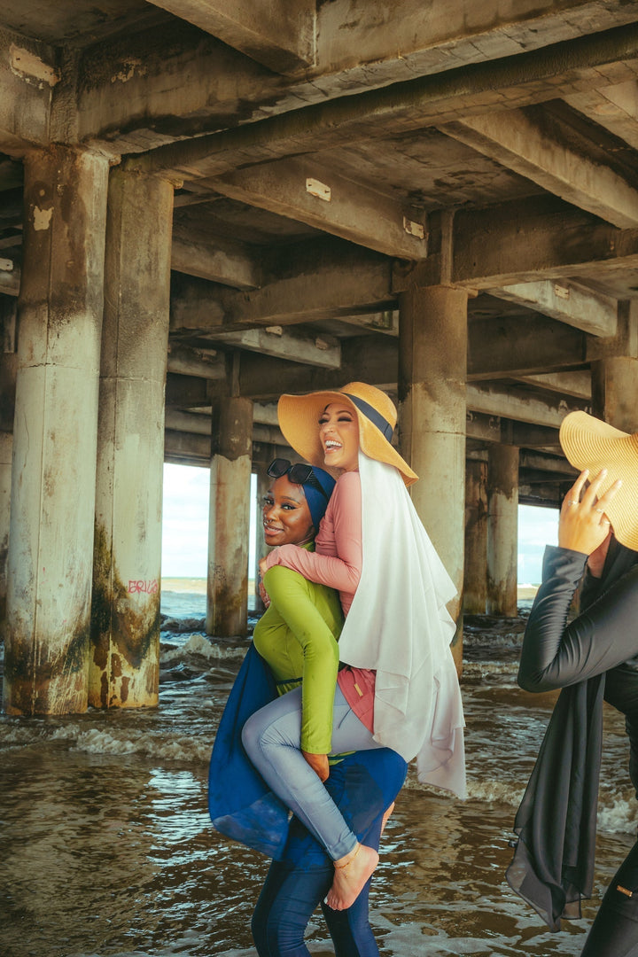 Three women in lime green piece modest swimsuit enjoying beach fun and comfort