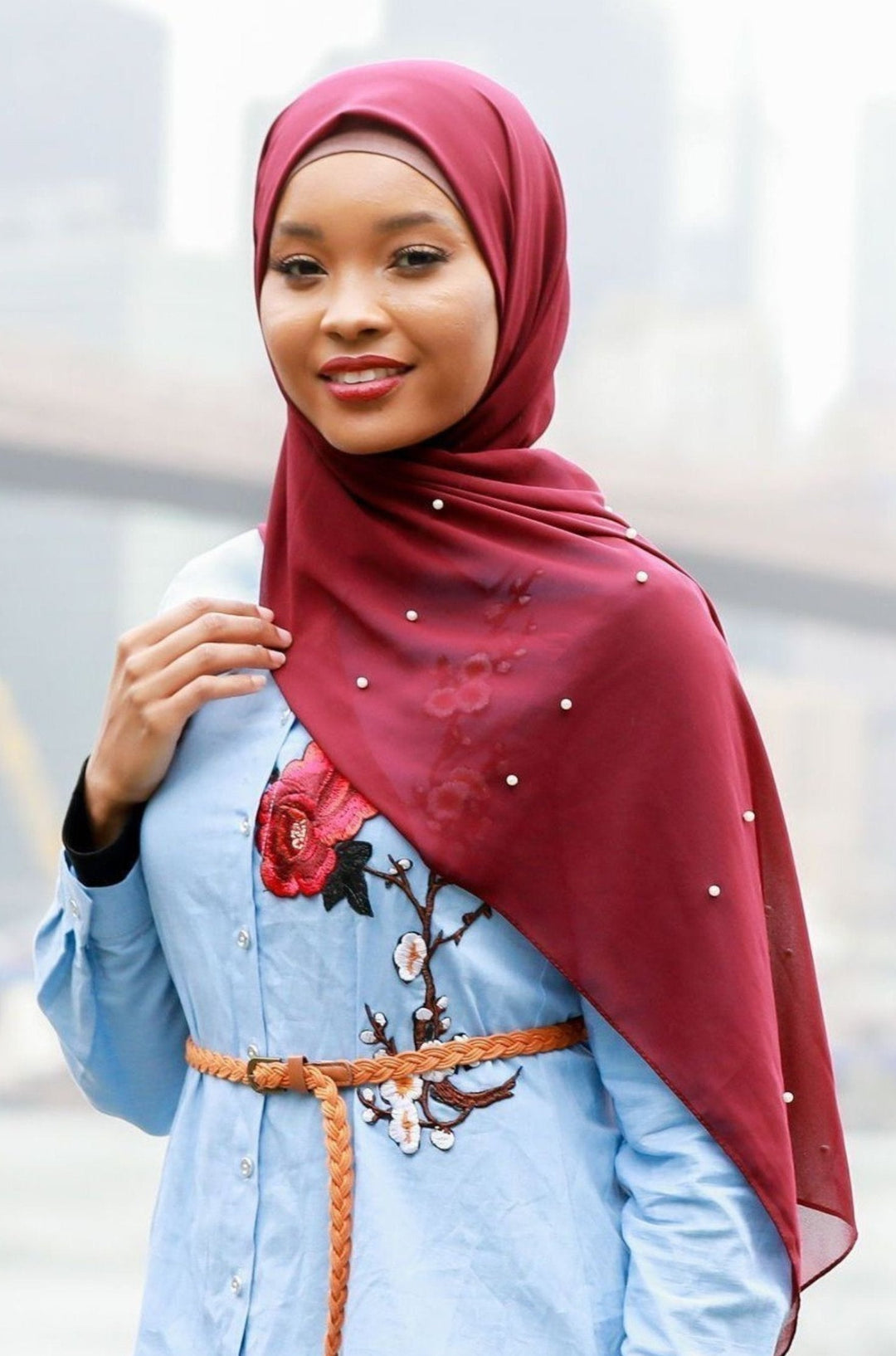 Woman in maroon hijab and light blue dress showcasing Maroon Pearl Chiffon Hijab