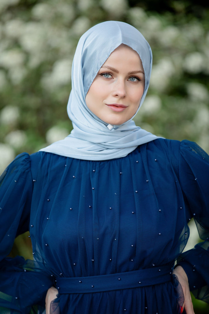 Woman in blue hijab wearing a Mesh Pearl Long Sleeve Gown displayed in various colors