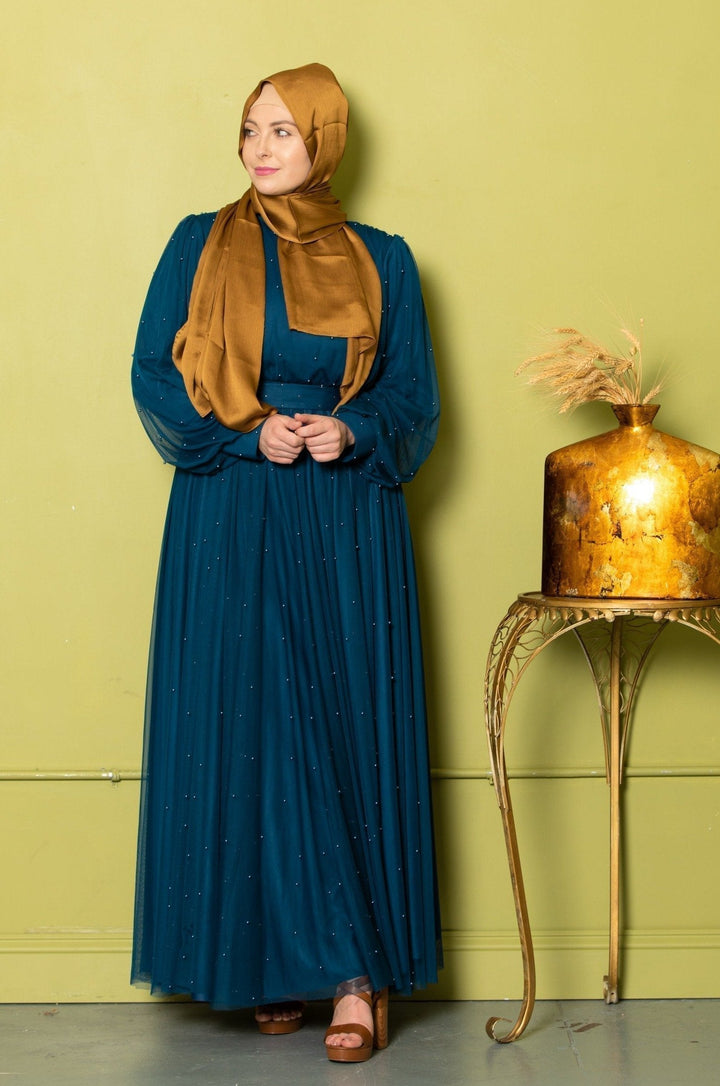 Woman in a teal Mesh Pearl Long Sleeve Gown with a gold hijab style