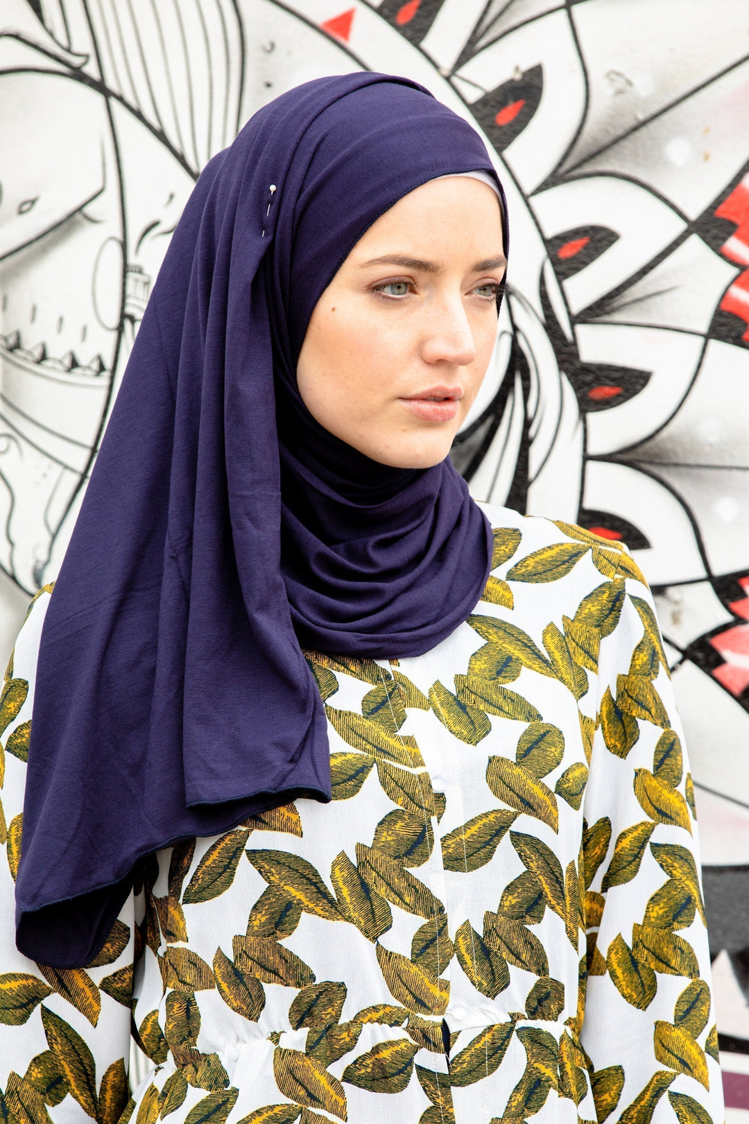 Woman in navy hijab and leaf-patterned dress showcasing Navy Blue Jersey Hijab