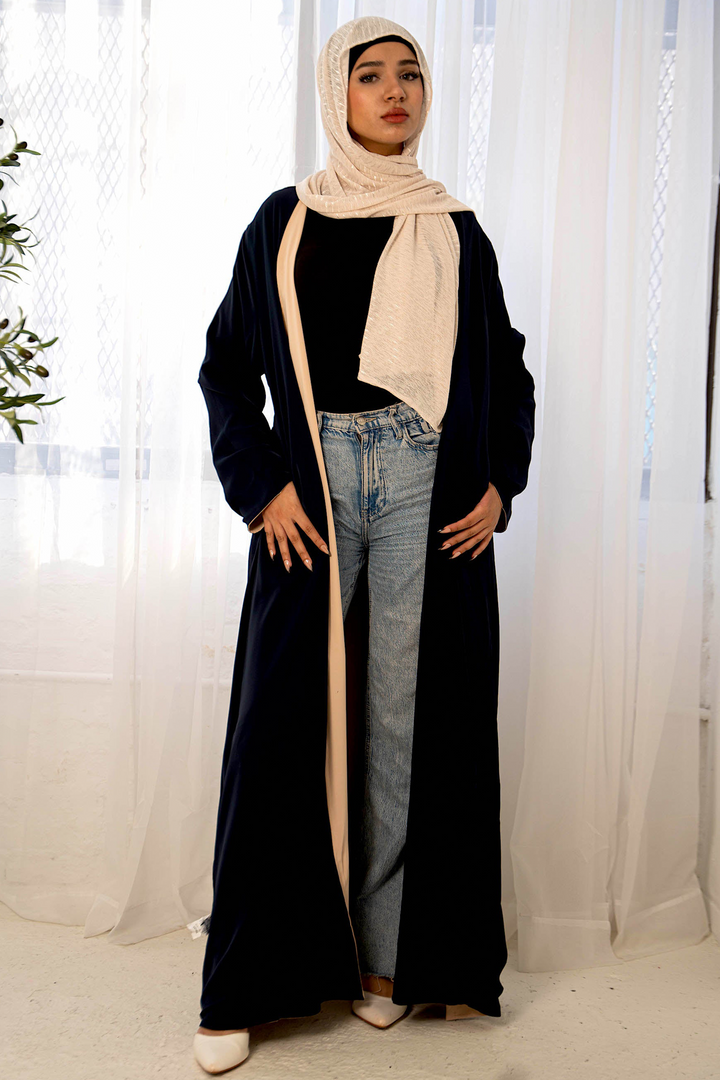 Woman in navy reversible open abaya with beige hijab and jeans, stylish maxi dress