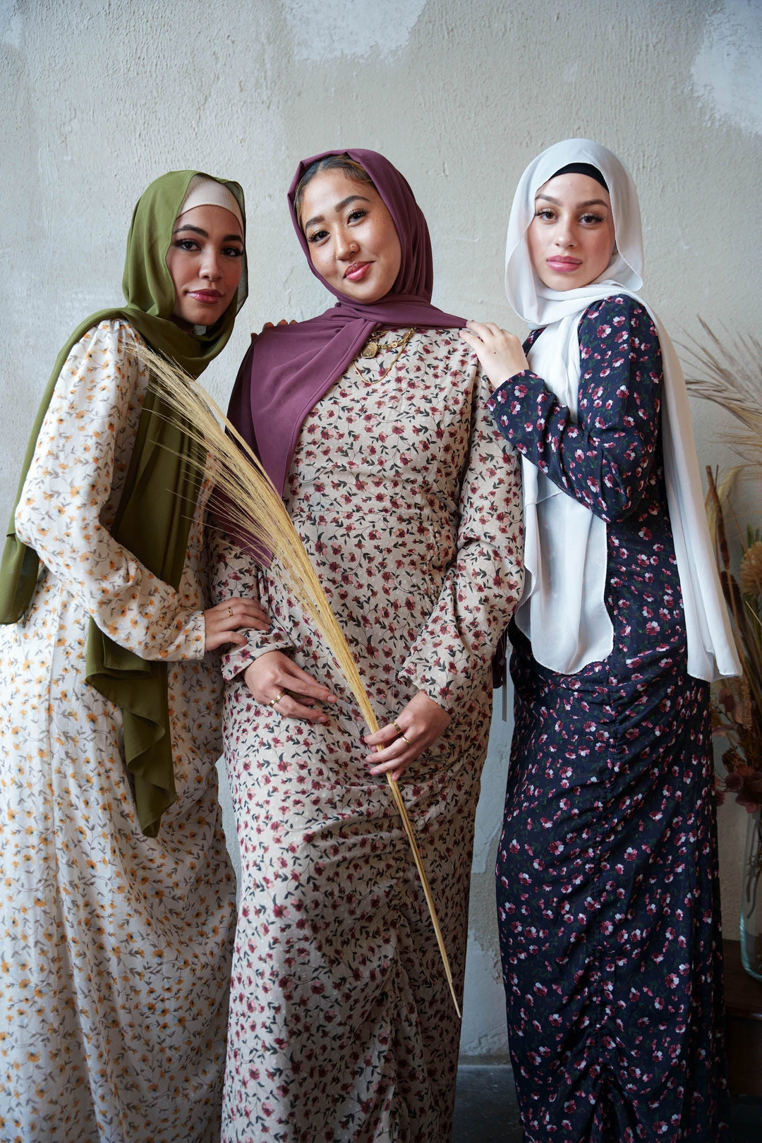 Three women in hijabs wearing Navy Floral Ruched Maxi Dresses showcasing adjustable ruching