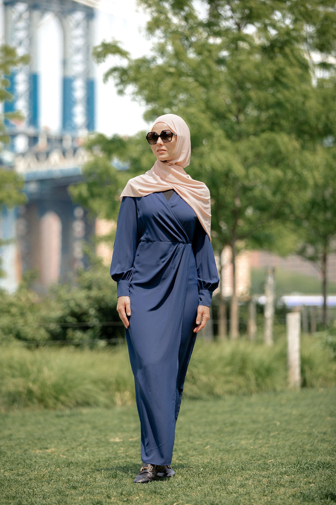 Woman in a blue wrap maxi dress with criss cross neckline on clearance display