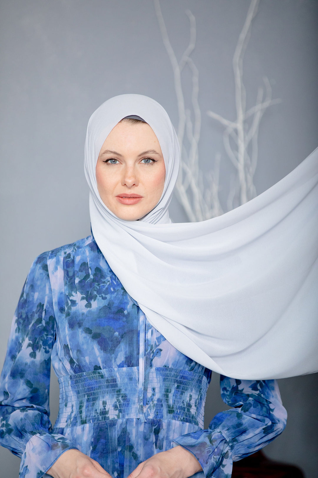 Woman in blue floral maxi dress with light gray chiffon scarf and hijab