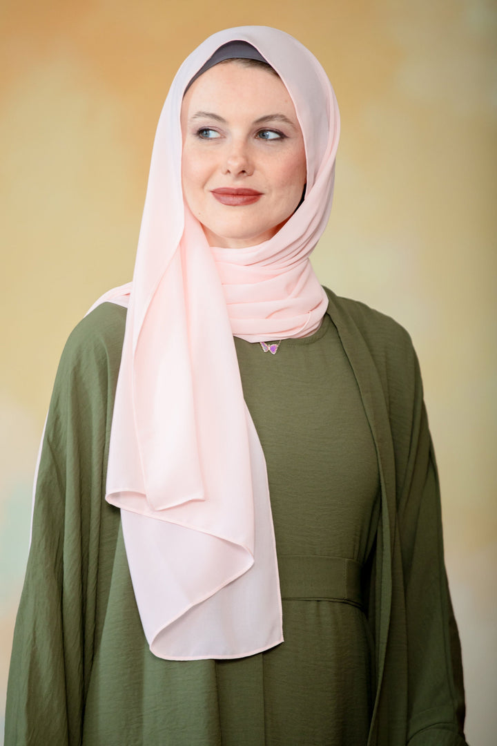 Woman in hijab wearing a stylish olive green maxi dress with a peach chiffon scarf