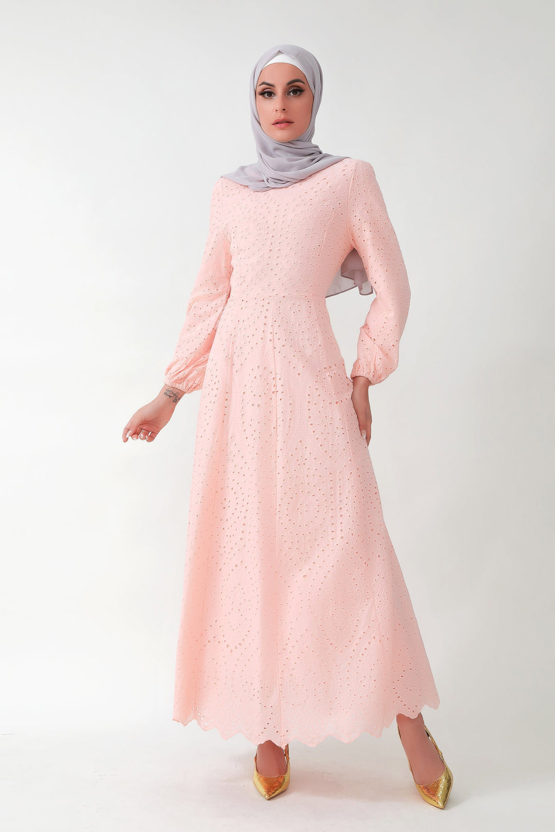 Woman in a peach eyelet long sleeve maxi dress with a gray hijab