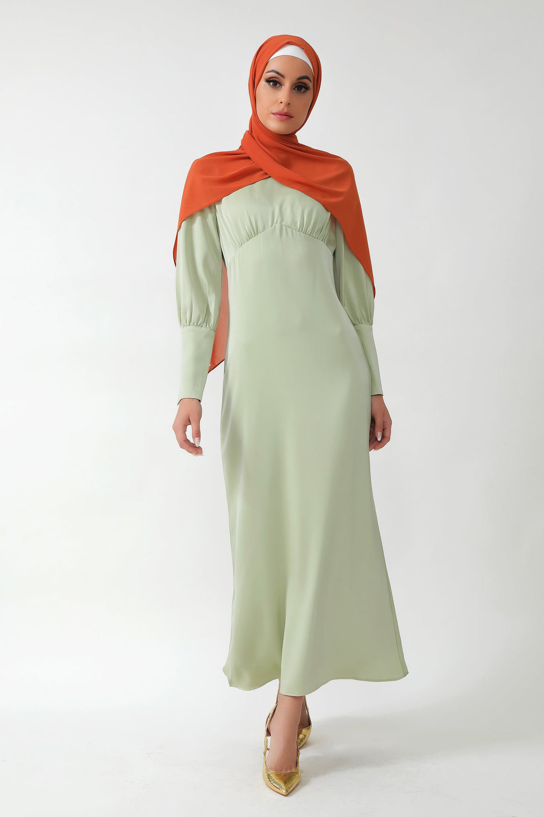 Woman in a light green dress and orange hijab wearing a Pistachio Satin Long Sleeve Maxi Dress