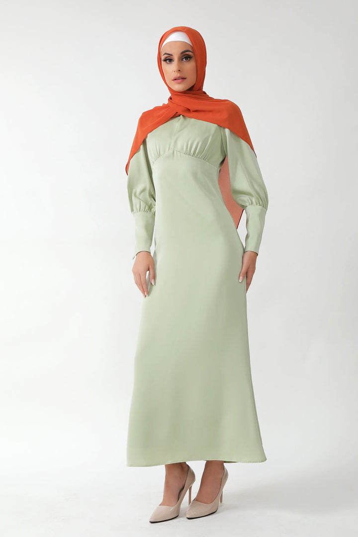 Woman in a Pistachio Satin Long Sleeve Maxi Dress with an orange hijab and batwing sleeves