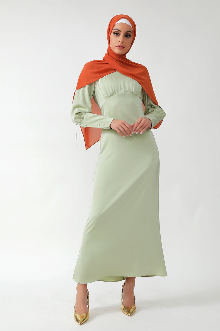 Woman wearing Pistachio Satin Long Sleeve Maxi Dress with orange hijab and batwing sleeves