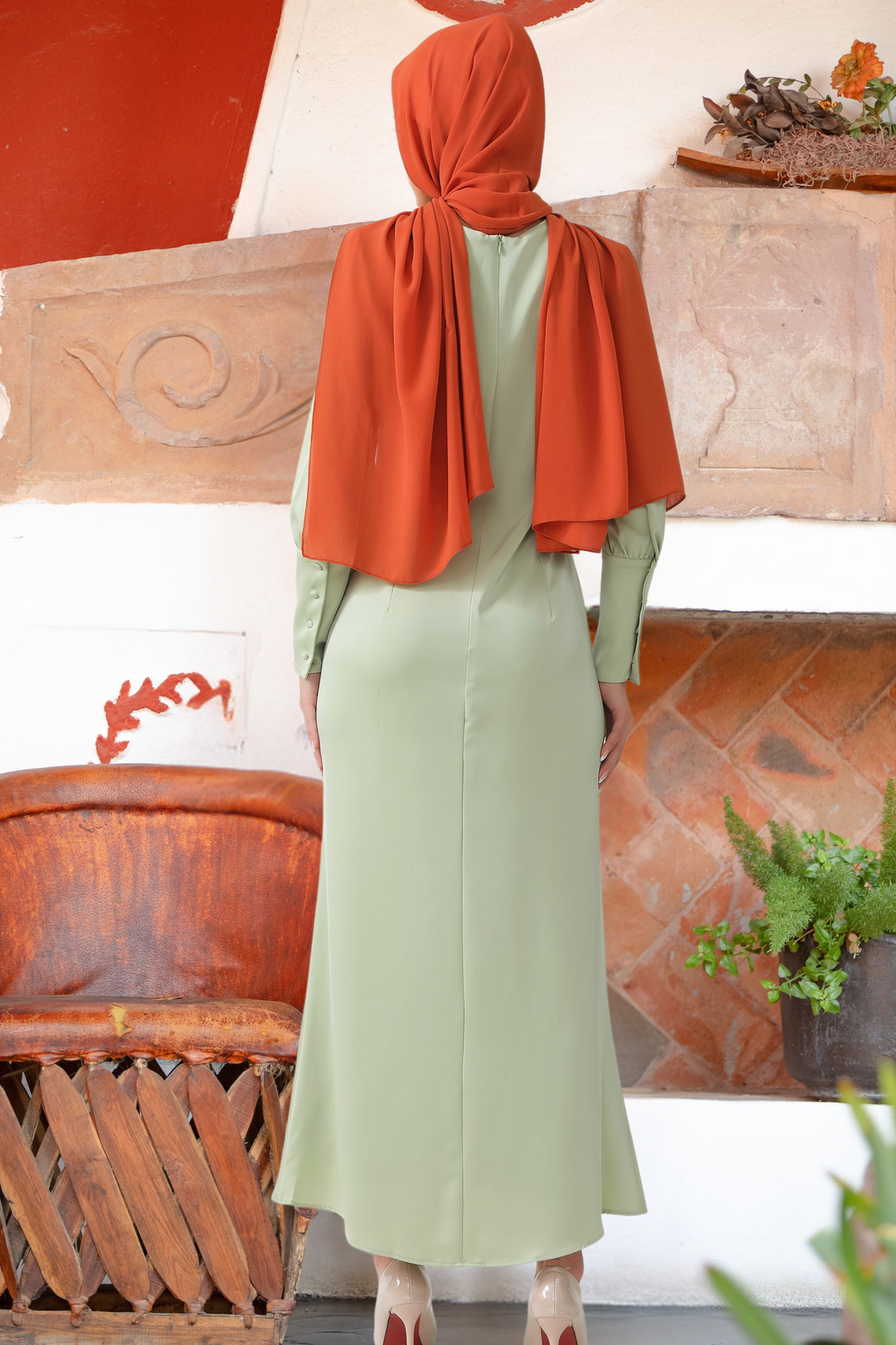 Woman wearing a Pistachio Satin Long Sleeve Maxi Dress with batwing sleeves and orange hijab